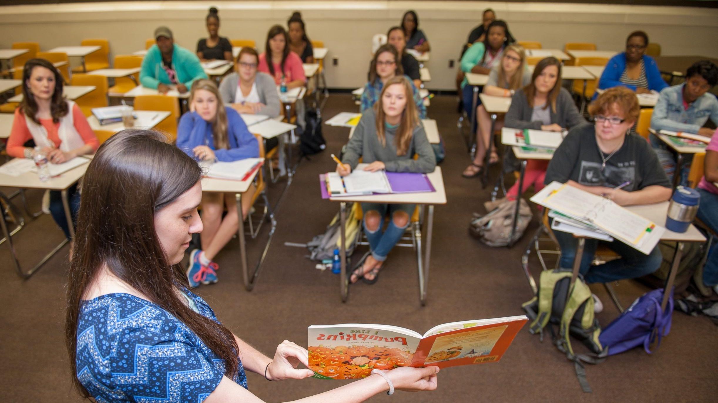 Student presenting children's book to classroom.